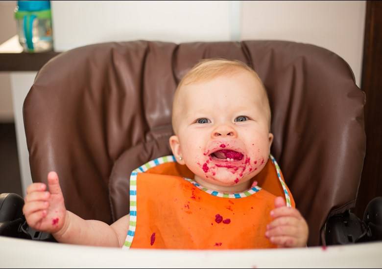 baby with beetroot on bib