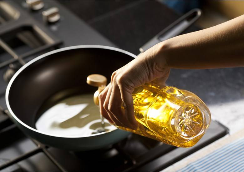 hand pouring oil in pan