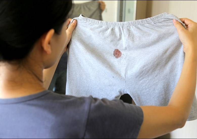 person holding up bloodstained pants
